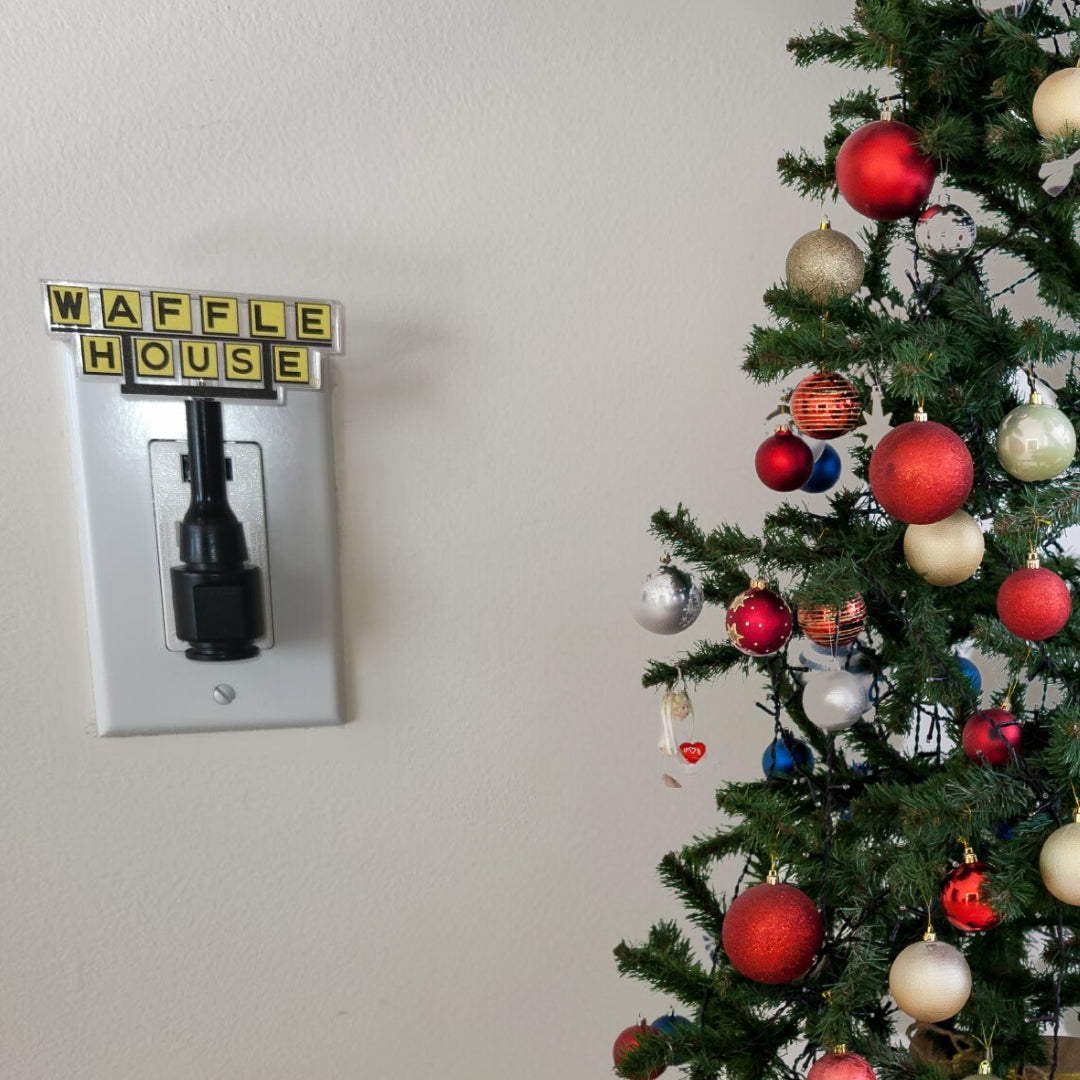 Waffle House nightlight plugged into outlet with Christmas tree on the right side