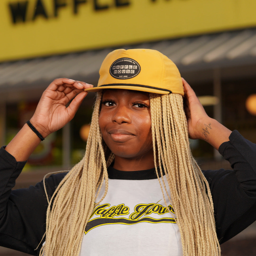 woman wearing retro yellow Waffle House patch hat