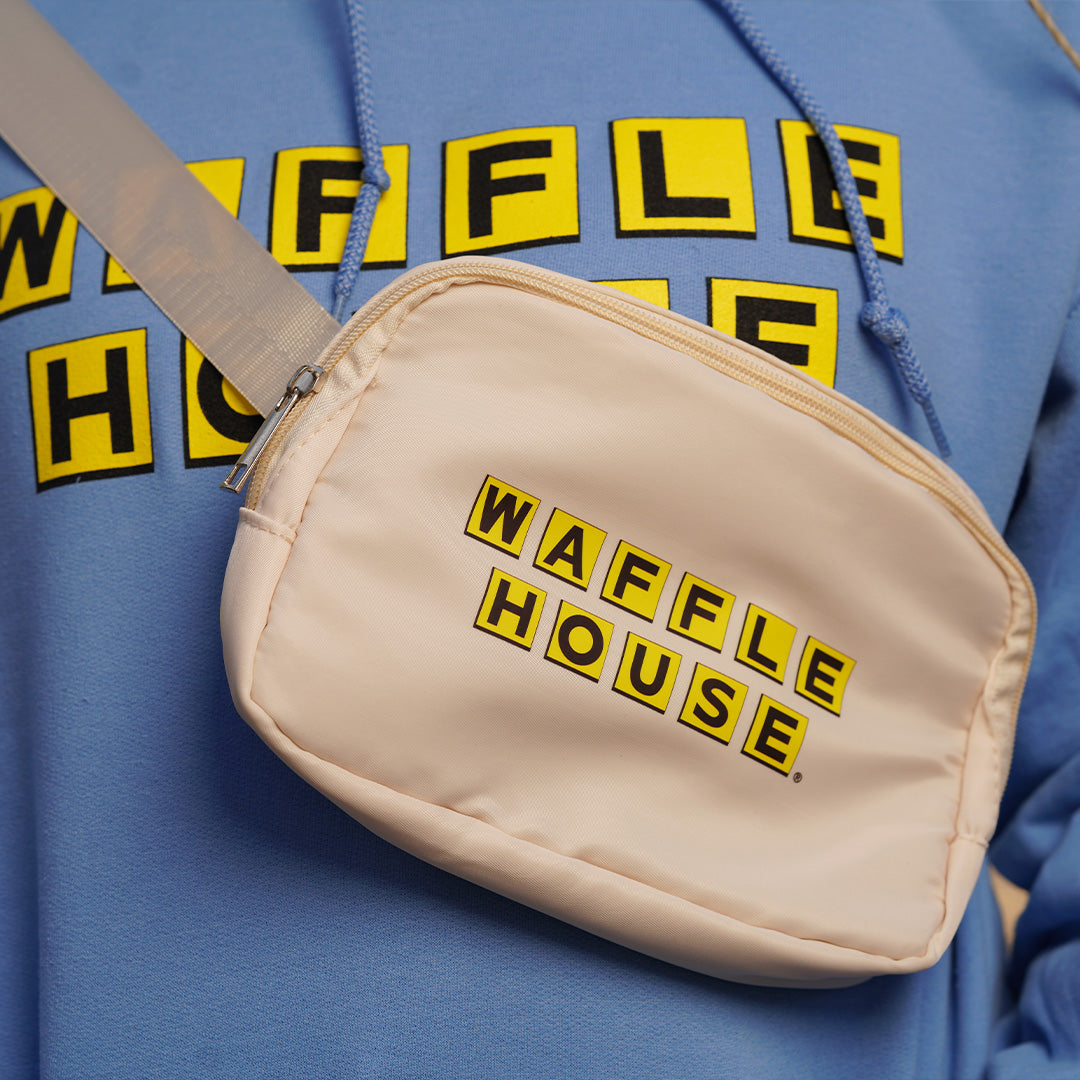 person wearing blue Waffle House hoodie with off white crossbody bag that has Waffle House logo on it