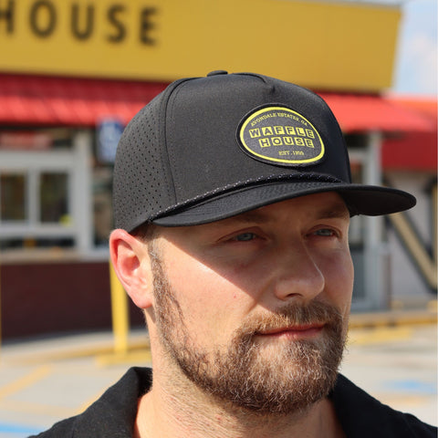 Man standing in front of Waffle House wearing a black hat with Waffle House woven patch.
