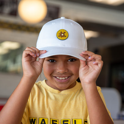 Child wearing a white cap with a yellow waffle pvc patch