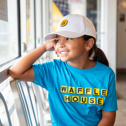 Child wearing a blue 'Waffle House' shirt and white cap with a waffle pvc patch.