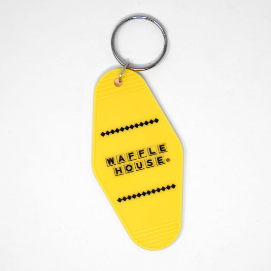 Yellow motel keychain with black Waffle House logo laying flat on white background