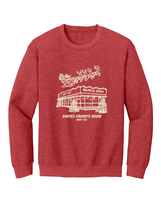 Red sweatshirt featuring a cream-colored drawing of a snowy Waffle House with Santa and his reindeer flying overhead, along with the words “Santa’s Favorite House Since 1955.