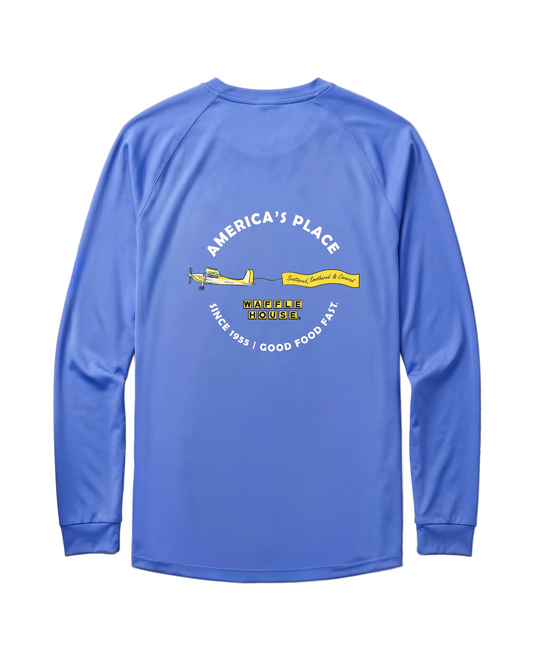 Back of bimini blue Waffle House performance long sleeve with arched "America's Place" text above a yellow banner plane pulling a "Scattered, Smothered & Covered" flag, Waffle House logo center, "Since 1955 – Good Food Fast" along bottom arc