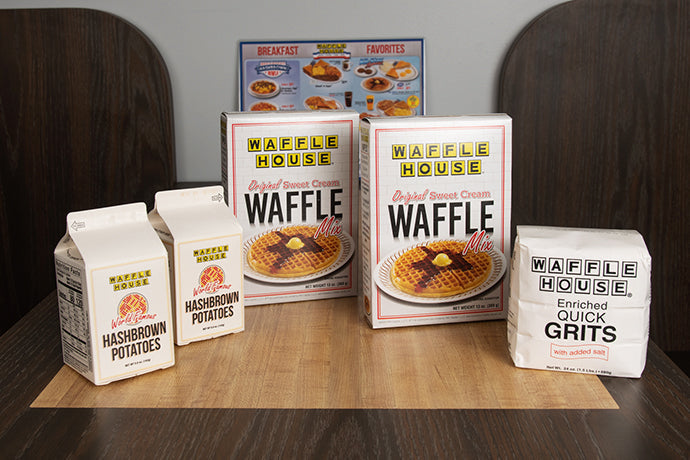 Two boxes of Waffle House waffle mix, two boxes of Waffle House hashbrowns and one pack of Waffle House grits sitting on table of a booth
