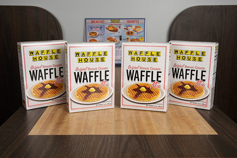 4 boxes of Waffle House waffle mix sitting on the table of a booth with a Waffle House menu in the background