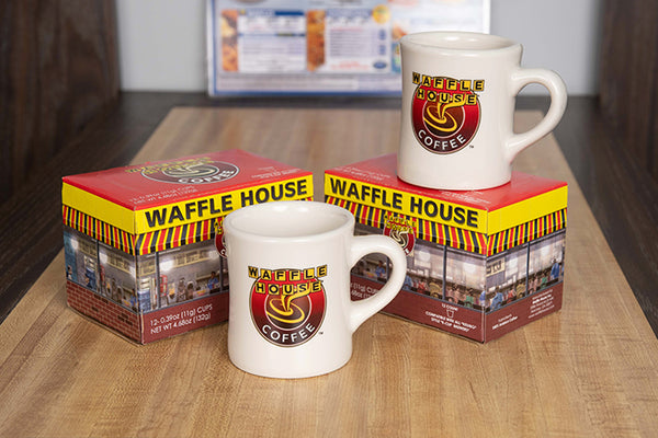 Two boxes of Waffle House coffee pods and two Waffle House classic mugs.