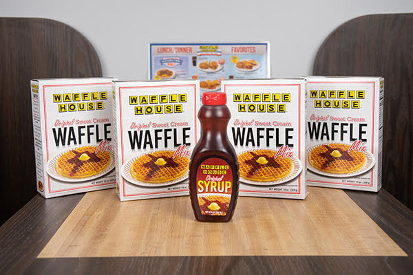 4 boxes of Waffle House waffle mix and one bottle of Waffle House original syrup sitting on the table of a booth